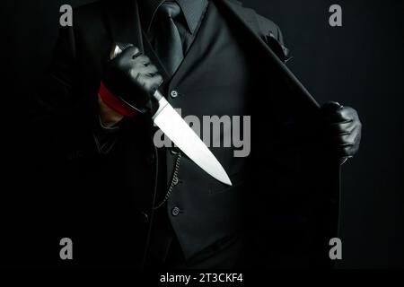 Portrait of Mystery Man in Black Suit Pulling Out Knife From Jacket. Horror Movie Killer Stock Photo