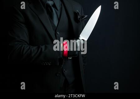 Portrait of Man in Dark Suit and Leather Gloves Holding Knife. Mafia Hit Man or Ruthless Gangster Stock Photo