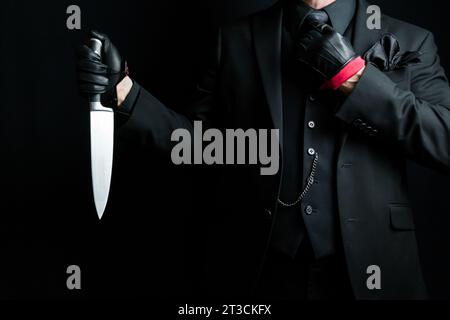 Portrait of Man in Dark Suit and Leather Gloves Holding Sharp Knife. Well Dressed Gentleman Killer. Mafia Hit Man in Stylish Suit. Stock Photo