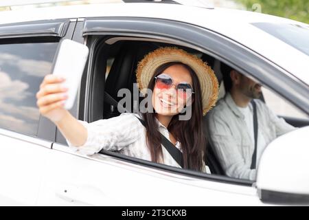 Stylish young woman taking selfie on phone during car ride Stock Photo