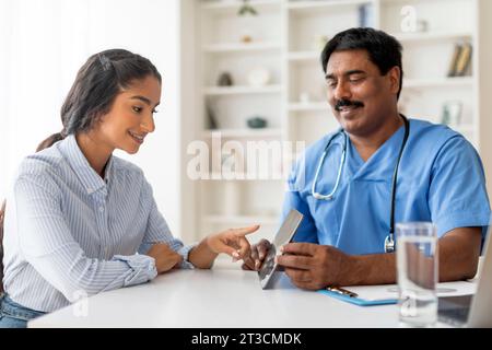 Medicine And Healthcare. Indian doctor showing digital tablet screen to female patient Stock Photo