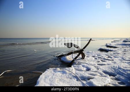 A close-up anchor at the icy ocean seashore Stock Photo