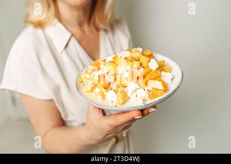 In the hands of a female nutritionist is a plate with a ready-made dish of zucchini and feta cheese. Close-up. Stock Photo