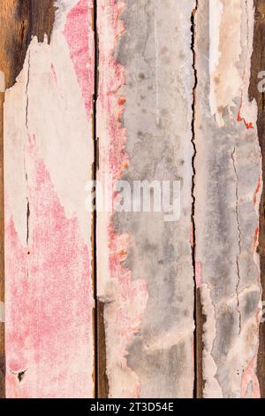 A weathered pink fence in Arles, France, shows peeling pink paint on its vertical planks, with brown wood beneath. Stock Photo