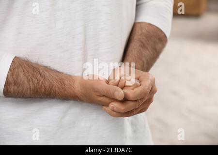 Man cracking his knuckles on blurred background, closeup. Bad habit Stock Photo