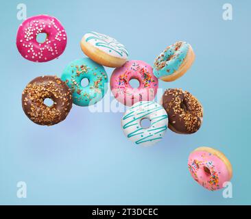 Different tasty donuts falling on light blue background Stock Photo