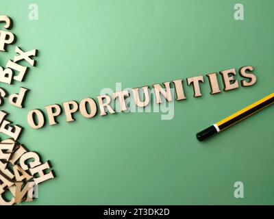 Wooden word and pencil with text OPPORTUNITIES on a green background. Stock Photo