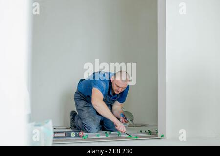 A male construction worker installs a large ceramic tile. Stock Photo