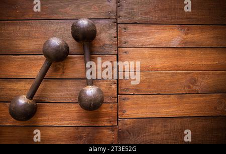Old rusty dumbbells on rustic wood board background texture Stock Photo