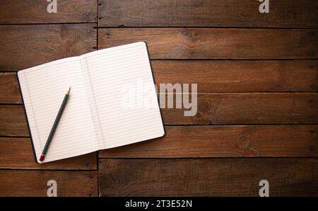 Open notebook and pencil on a rustic vintage wooden board Stock Photo