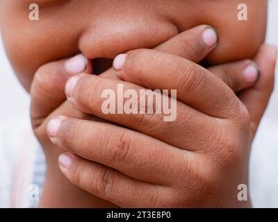 close up of little boy covering mouth Stock Photo