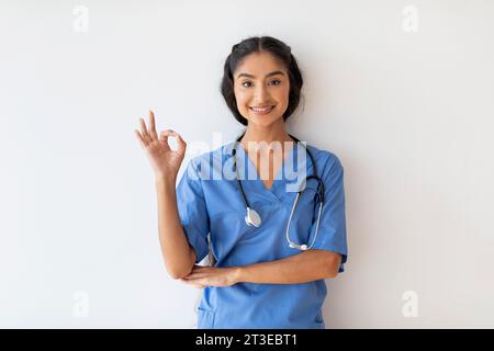 Portrait of happy young indian doctor woman in uniform showing okay gesture Stock Photo