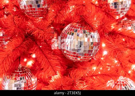 Christmas disco ball on a red Christmas tree. new Year's background. Decorated Christmas tree. Stock Photo