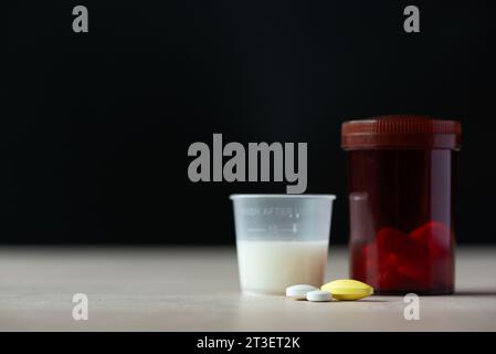 Tablets of medications, liquid medicine and platic container on the table Stock Photo