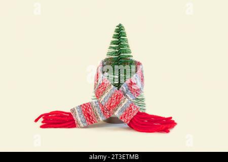 Christmas Tree in a Scarf. Creativity Image of Cold Season. Heating System, Winter is Coming Creative Concept. Model of a House Wearing a Knitted Warm Stock Photo