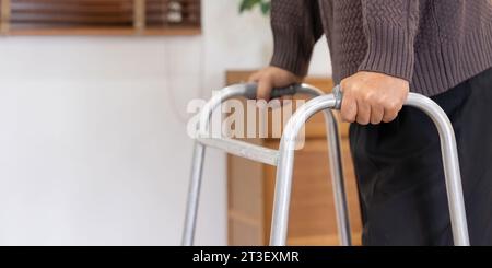 Close up of senior man with disability leaning on walker to move along the room Stock Photo