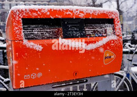 Leiden, Netherlands, 10 December, 2017: image of the orange mailbox owned by the Post NL, Holland post service under the snow Stock Photo