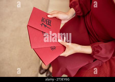 Close up of young woman holding red card with Chinese New Year blessings in traditional calligraphy Happiness inscription Stock Photo