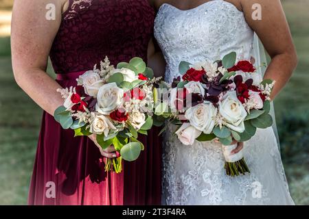 Bride with bridesmaid holding flower bouquets in their hands Stock Photo