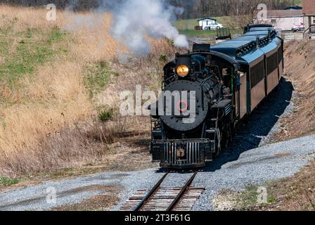 A Front and Slightly Above View of an Approaching Restored Narrow Gauge Passenger Steam Train Blowing Smoke and Steam on a Sunny Winter Day Stock Photo