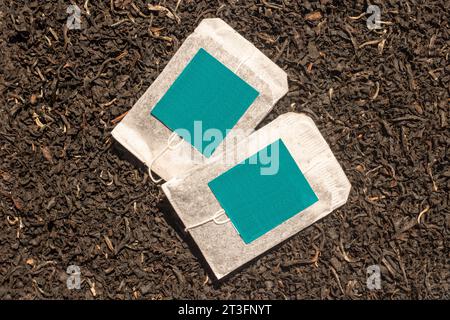 Tea bags on black tea leaves as background background. Top view. Copy space for text Stock Photo