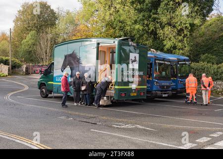 Customers waiting whilst the steps are  lowered --- for  the entrance of the  mobile bank facility provided by Lloyds Bank....Whitefriars Settle. Stock Photo