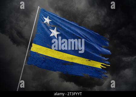 Curacao torn flag on dark sky background. Stock Photo