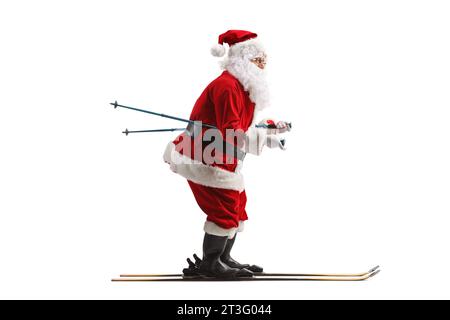 Full length profile shot of Santa Claus skiing isolated on white background Stock Photo