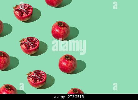 Trendy fruit pattern made of fresh red pomegranates on light pastel green background with copy space. Minimal healthy food layout. Nature concept. Stock Photo