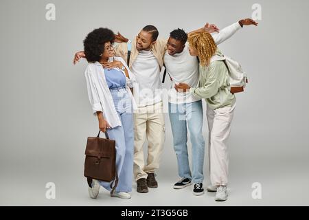 joyous african american friends smiling at each other cheerfully on gray background, students Stock Photo