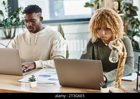 two good looking concentrated coworkers working at their laptops on project, business concept Stock Photo