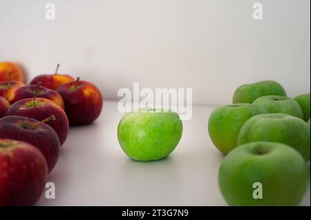Two groups of green and red apples. One apple in the center. Organic fresh fruits and image of autumn harvest Stock Photo