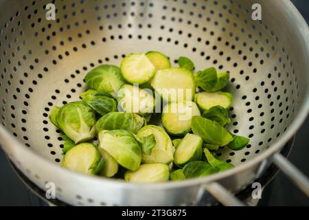 Brussels sprouts steaming in a sieve on top of the kettle, close up view. Stock Photo