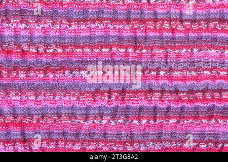 Abstract knitted colorful background. Wave pattern of pink, blue, yellow, purple knitting threads. Close-up of a knitted blanket. Copy space Stock Photo
