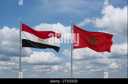 Morocco and Egypt flags waving together on blue cloudy sky, two country relationship concept Stock Photo