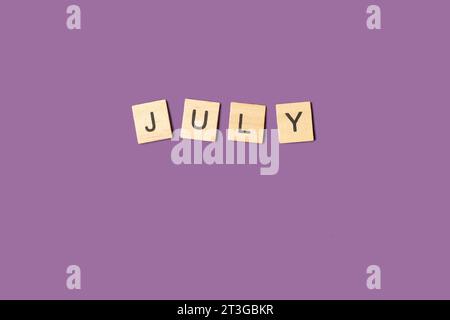 July single word made with wooden letter blocks on an purple background with copy space Stock Photo