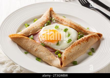 Galette complete Breton buckwheat pancake with egg cheese and ham closeup on the plate on the table. Horizontal Stock Photo