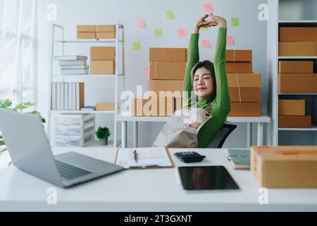 Small business, online business owner, young woman is using profit calculator and checking inventory Stock Photo