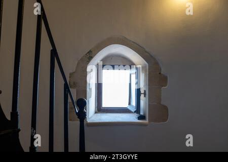 Interior of Gavdos Lighthouse, Crete island Greece. Outdoors view through an open small window in front of metal ladder. Illuminated wall Stock Photo