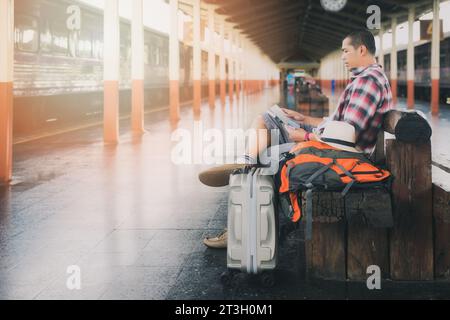Traveler sitting and using map at train station. Stock Photo
