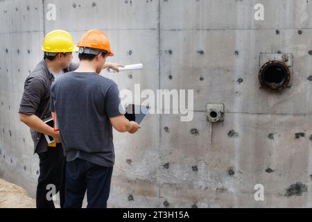 Team of construction workers discussing project details with blueprint in construction site. Stock Photo