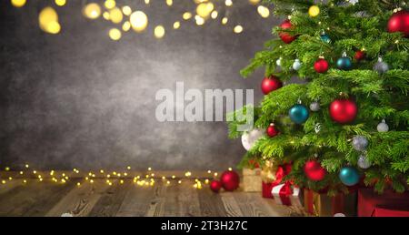 Delightful Christmas tree closeup with textured gray wall as a nice background framed with lights and vignetting Stock Photo