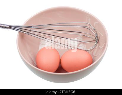 Manual egg beater and three eggs in a ceramic bowl, isolated on white background Stock Photo
