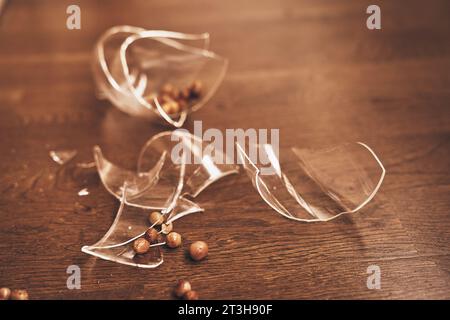 Transparent mug broken close-up of compote with raisins. Pieces of broken glass lie on the floor with space to copy. High quality photo Stock Photo