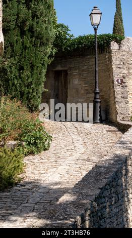 Alley of Lovers, a narrow stone path with a classic iron lantern at the beginning of the road in the city of Gordes, France. Stock Photo