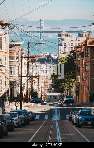 looking down Washington St, San Francisco, toward the Oakland Bridge, on an autumn afternoon. Power lines sprawl while cable car tracks run parallel Stock Photo