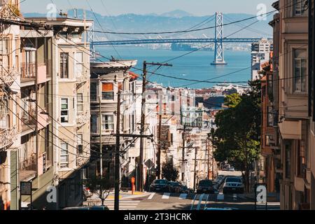 looking down Washington St, San Francisco, toward the Oakland Bridge, on an autumn afternoon. Power lines sprawl while cable car tracks run parallel Stock Photo