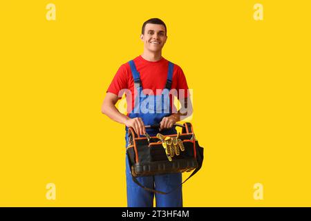 Male car mechanic taking tools from bag on yellow background Stock Photo