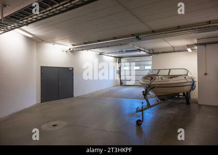 White motorboat on transport cradle in underground garage on parking lot. Sweden. Stock Photo