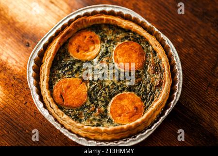 A freshly prepared cheese and spinach pie, its golden crust glistening on a wooden surface, a delectable option for vegetarians Stock Photo